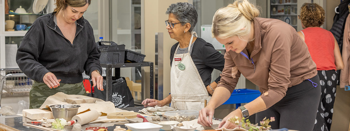 group of people working on an introductory pottery class